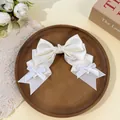 Close-up of a white satin Lolita-style bow hair clip with dainty ribbon accents - Beige