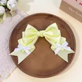 Detail view of pale yellow Lolita style satin bow hair clip on wooden plate - Yellow