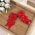 Detail view of a vibrant red Lolita style triple-layer satin bow hair clip texture. - Red