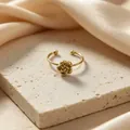 Detailed macro shot of an elegant gold camellia flower ring on a textured stone base. - Single Camellia Ring (Gold)