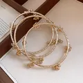 Vintage gold bangles with dangling flower charms in a leather tray - Twisted Loop Flower Charm Bangle Set (37) / Gold