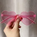 Close-up detail of trendy transparent pink heart-shaped jelly sunglasses held in hand - Pink