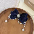 Λεπτομερής προβολή ενός κομψού μπλε κλιπ μαλλιών με φιόγκο και μαργαριταρένια φούντα. - Ναυτικό μπλε