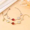 Detail view of dainty ladybug and white shell flower charms on elegant link chain bracelets - Rose Gold Case White Dial / 18K Gold