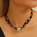 Close-up van een luipaardprint choker met een grote reflecterende gouden bol hanger - Bol Stijl (X1826A)