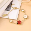 Close-up of gold bracelet featuring red ladybug and mother of pearl flower charms - Gold White / 18K Gold