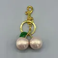 Detailed view of the cherry-shaped bag charm with pink pearl finish spheres and golden hardware. - Pink With Green Leaf