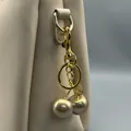 Nahaufnahme eines luxuriösen goldenen Kirsch-Taschenanhängers an einer beigen Handtasche - Gold