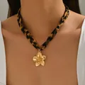 Primo piano di una collana leopardata con un ciondolo a forma di fiore dorato dettagliato. - Stile Fiore (X1826F)