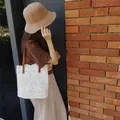 Detailansicht einer weißen Häkel-Strandtasche aus Spitze mit Lederriemen. - Gebrochenes Weiß