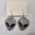 Silberne Glitzer Alien Kopf Ohrhänger mit Haken auf einer weißen Displaykarte präsentiert - Dunkelsilbernes Pulver