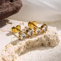 Detailweergave van gouden titaniumstalen strikoorbellen met heldere hartkristallen. - 5778 Oorbellen Met Strik En Diamant
