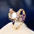 Vue macro d'une bague de princesse féerique avec pierre de lune et cristaux violets - Style Ailé Rose et Violet (R05508-01) / Doré