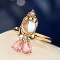 Vue macro d'une bague de princesse de conte avec pierre de lune irisante et gemmes roses - Style Coeur Doux Rose (R05511-01) / Doré