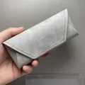 Détail rapproché d'un étui à lunettes pliable gris à texture marbrée avec coutures jaunes - Gris clair