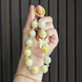 Close-up detail of a candy-colored beaded phone charm featuring a yellow ring and bow - Yellow