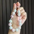 Detailed view of iridescent pearly beaded keychain featuring a cute pink bow ornament - Pink