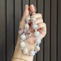 Detailed view of pearlescent beaded keychain with a matte brown bow charm accessory - Coffee