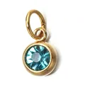 Macro view of a gold-plated stainless steel pendant with a light blue birthstone crystal. - December Birthstone (6mm)