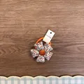 Detaillierte Ansicht eines niedlichen Blumen-Haargummis mit gepolsterten Blütenblättern - Orange Floral