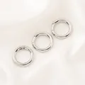 Vue détaillée de trois fermoirs à ressort circulaires argentés sur fond de soie blanche. - Boucle à Ressort Ronde (18mm) / 1 Pièce / Or blanc