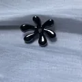 Vue macro d'une perle de bijoux DIY noire brillante en forme de fleur sur tissu texturé - Perle de Fleur à Six Pétales / 5 Pièces / Canon de fusil