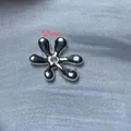 Gros plan d'un accessoire de bijoux DIY argenté en forme de fleur avec trou central - Perle de Fleur à Six Pétales / 5 Pièces / Argenté