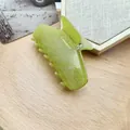 Detailed view of a lime green glitter cat-shaped acetic acid hair claw clip on a wooden tray - Olive Glitter