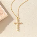 Goldene Halskette mit einem Zirkonia Kreuzanhänger auf beigem Hintergrund. - C00187 / 18K-Gold