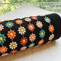Gros plan de chaînes marguerites en émail coloré sur velours noir, acier inoxydable doré 18 carats. - Modèle Émail Coloré / Doré