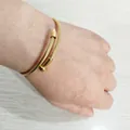 Detail shot of a gold nail-shaped twisted cable cuff bracelet worn on a wrist. - Gold (YB-004G)