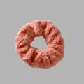 Vue détaillée d'un chouchou en peluche rose doux soulignant la texture duveteuse et l'élastique - Orange