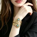 Detail of a vintage gold cuff bracelet with turquoise stones on a woman's wrist - Interlocking Openwork Turquoise