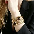 Detailed view of a vintage gold layered cuff bracelet with dark cabochon stones. - Multi-layered Hollowed-out Brown