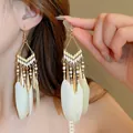 Detailed view of Bohemian long earrings with white feathers and gold-tone beads - Ear Hook - Yellow Feather