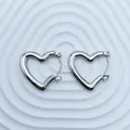 Macro view of polished silver-tone stainless steel heart-shaped hoop earrings on white - 18K Gold / Silver High Polish Heart (099)