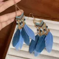 Close-up of bohemian blue feather drop earrings with gold metal chains and beads - Ear Hook - Blue Feather