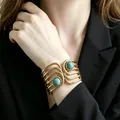 Close-up of retro gold-tone wide cuff bracelet with dual turquoise stones on model - Multi-layered Hollowed-out Turquoise