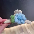 Close-up detail of a handmade winter knitted blue flower hair claw clip accessory - Blue