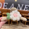 Close-up of hand-knitted flower hair claw clip featuring soft white and pink yarn details - White
