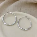 Macro view of polished silver-plated twisted hoop earrings on a minimalist stone dish - Twisted Texture Hoop (YG4810) / 4cm Size / Silver