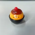 Simpatico giocattolo antistress a forma di budino di foca in una piccola ciotola nera - Foca Budino / Arancione