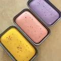 Set mit drei bunten Slow-Rebound-Squishy-Brotspielzeugen in grauen Behältern. - Taro-Box-Kuchen