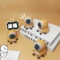 Detailansicht von vier niedlichen Capybara-Quetschspielzeugen auf dekorativen Büchern - Sitzendes Capybara / 6x4