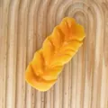 Realistisches Brot-Squishy-Spielzeug zum Stressabbau auf einem Holztablett-Hintergrund - Kleines Geflochtenes Brot