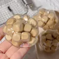 Macro di una mano che tiene una pallina antistress trasparente piena di cubetti di legno - Pallina in Legno
