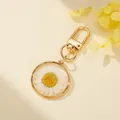 Macro view of a resin keychain featuring a real white dried daisy flower encapsulated in gold - White Round Daisy