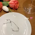 Detail view of a dainty silver bow slider bracelet with sparkling cubic zirconia on a plate - Bow (bracelet)