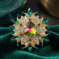 Vintage gold-tone brooch featuring an iridescent center stone with green crystal accents - White Rhinestone & Peacock Green Acrylic with Colored Glass Radial
