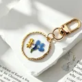 Handmade resin keychain featuring a real blue dried flower and gold charm pendant - Blue Flower